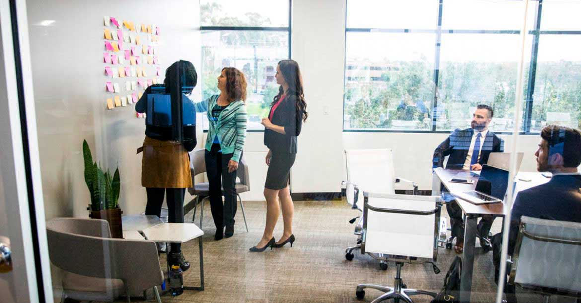 Colleagues in the meeting room standing by the kanban wall