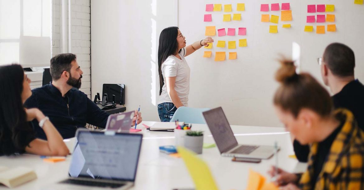 Casually dressed colleagues in the boardroom looking at the kanban wall