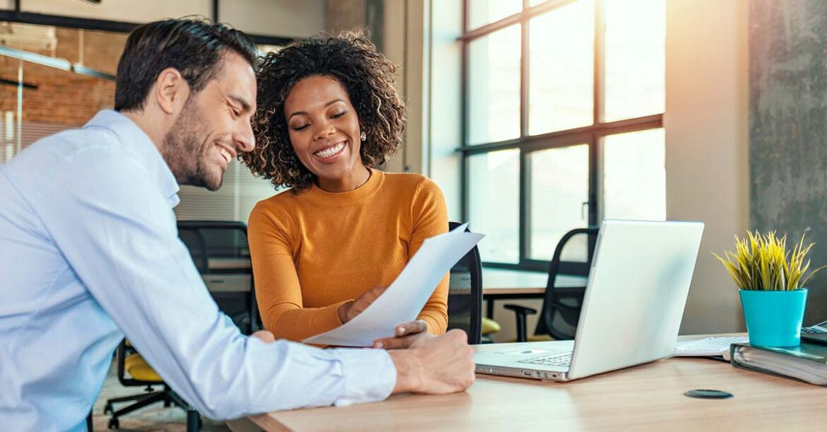 Two colleagues smiling and looking at the documents