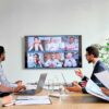 Diverse employees on online conference video call on tv screen in meeting room