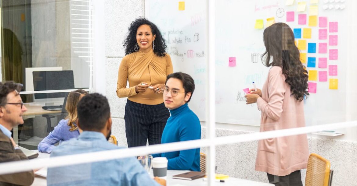 Female leader standing by a whiteboard guiding her team