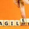 Finger moving letter blocks from spelling agile to agility