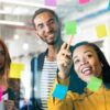 Young professionals planning tasks on glass wall with Kanban visual technique