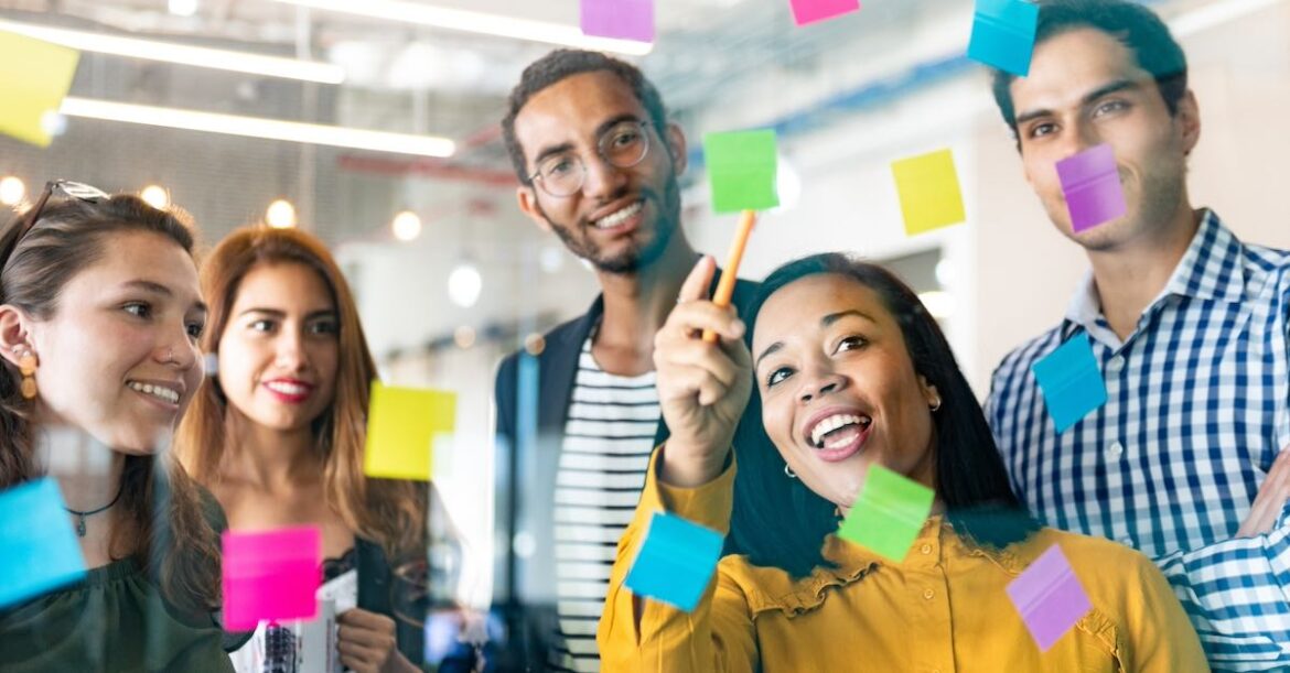 Young professionals planning tasks on glass wall with Kanban visual technique